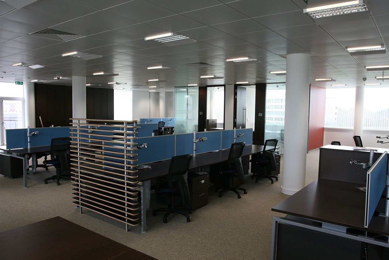 An empty office with desks, chairs and under desk storage.