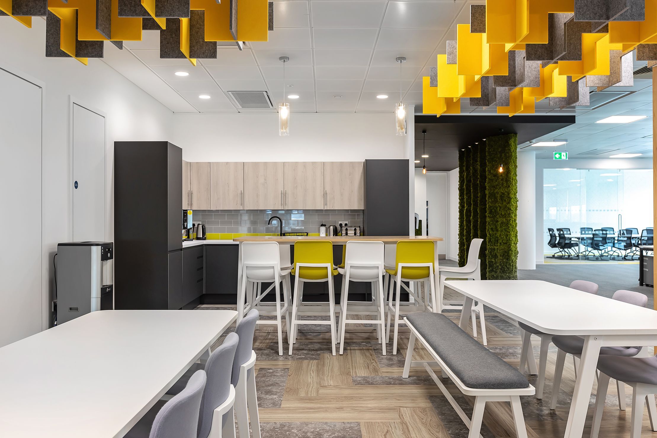 A colourful office kitchen with dark grey counters and white countertops.