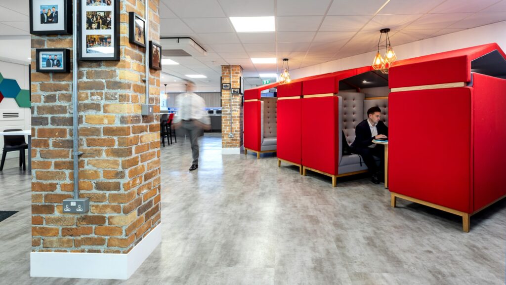 Image showcasing a workplace design with back to back red call/meeting booths, for a more private workspace option.