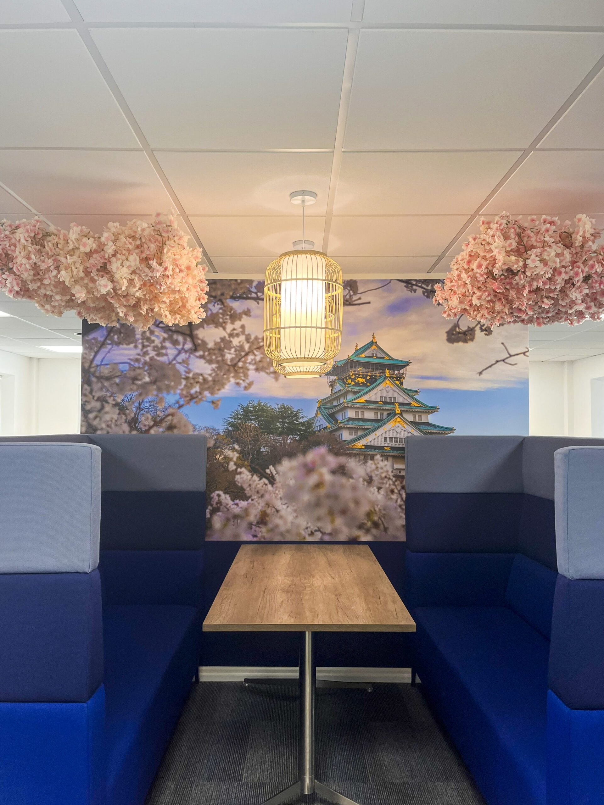 collaboration space with blue meeting booth and pink blossom on the ceiling. 